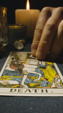 Vertical-Video-Close-Up-Shot-Of-Person-Giving-Tarot-Card-Reading-Laying-Down-The-Death-Card-On-Table